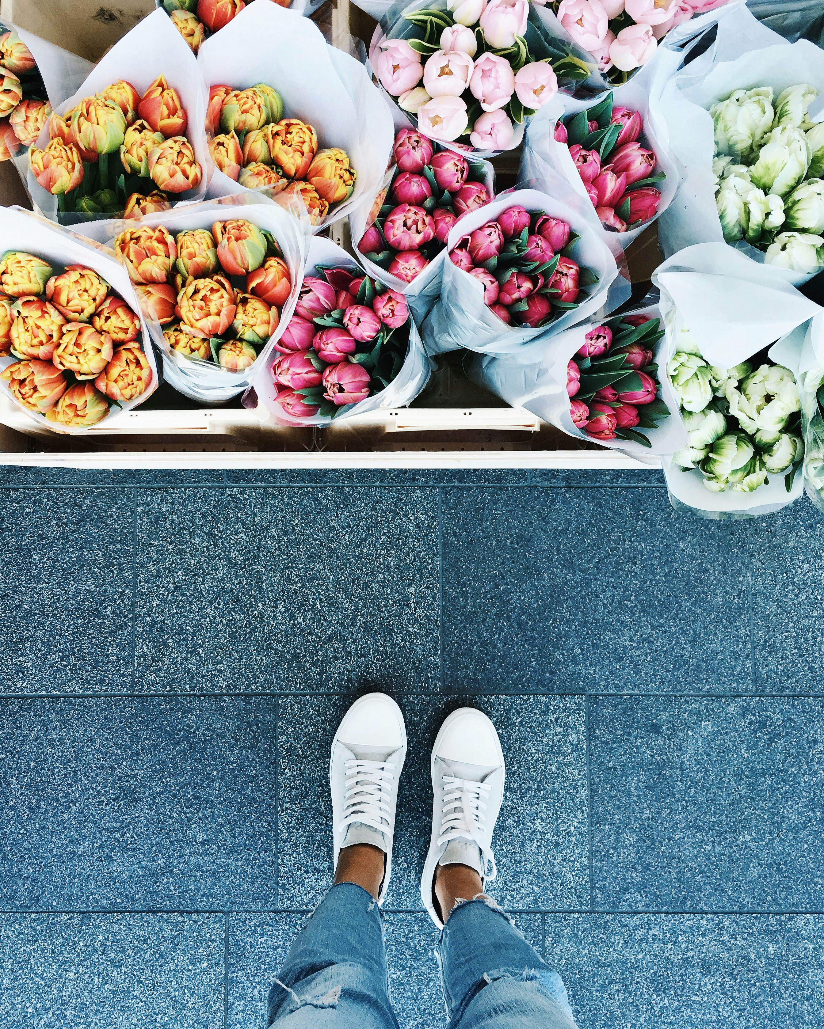 A person looking down at various flower bouquets.